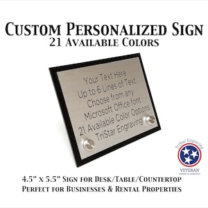 May include: A silver and black sign with a black border. The sign is 4.5 inches by 5.5 inches and has the text "Your Text Here Up to 6 Lines of Text Choose from any Microsoft Office font 21 Available Color Options TriStar Engraving" on it. The sign is for a desk, table, or countertop.