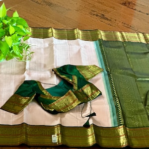 Baby pink and emerald green border with a tinge of orange weave and beautiful mayil! Pure silk and 2 gram zari. Stitched blouse size 38.
