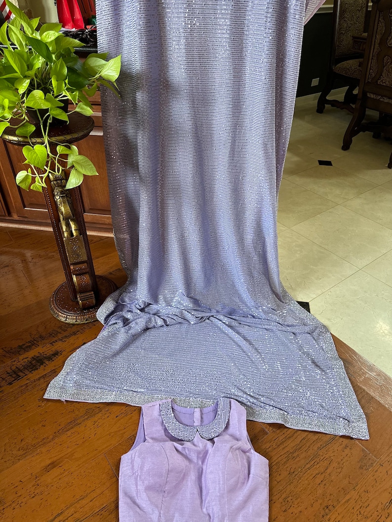 Pode incluir: Uma blusa sem mangas de cor lil&aacute;s claro com uma gola branca e um tecido de lantejoulas no fundo.