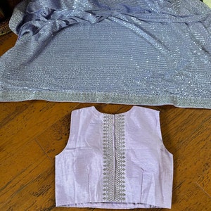 Pode incluir: Uma blusa sem mangas lavanda com um design bordado em prata nas costas.