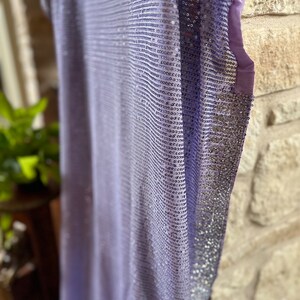 Pode incluir: Um top de lantejoulas lavanda com acabamento prateado. O top &eacute; feito de um tecido macio e leve e tem um caimento solto.