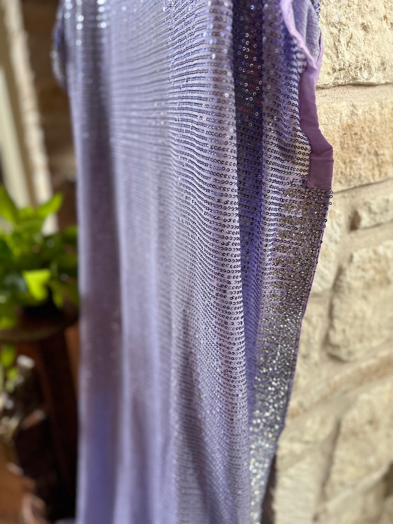 Pode incluir: Um top de lantejoulas lavanda com acabamento prateado. O top &eacute; feito de um tecido macio e leve e tem um caimento solto.