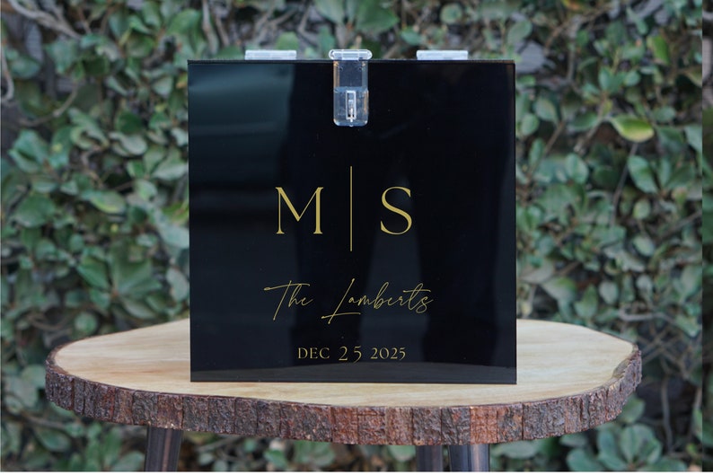 May include: Black acrylic box with a gold inscription. The inscription reads "M|S The Lamberts DEC 25, 2025".