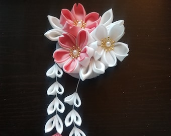 May include: A pink and white fabric flower hair ornament with dangling pink and white fabric leaves and gold bells.