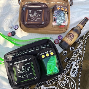 Puede incluir: Dos bandoleras, una marrón y otra negra, con múltiples bolsillos y texto. La bolsa marrón tiene un bolsillo transparente con naipes. También se ve una botella de Sunset Sarsaparilla y chapas. Las bolsas tienen el texto "Status S.P.E.C.T.A.L."