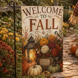 Puede incluir: Una bandera de jardín rectangular con el texto Welcome To Fall en letras marrones. El diseño incluye una linterna encendida, una caja de madera con las palabras Grateful Thankful Blessed, flores otoñales, calabazas y un pájaro.