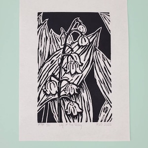 May include: Black and white woodblock print of a lily of the valley flower. The print is signed "MVO 2022" and numbered "Pt Ed. 1/50".