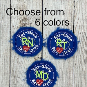 May include: Three blue embroidered patches with white text that reads "Eat-Sleep" and "Save Lives". The patches feature a red heart with a heartbeat line and a different medical profession's initials in the center: RN, RT, and MD.