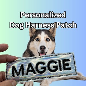 May include: A silver iridescent dog harness patch with black embroidered text that reads "MAGGIE". A husky dog is holding the patch in its mouth.