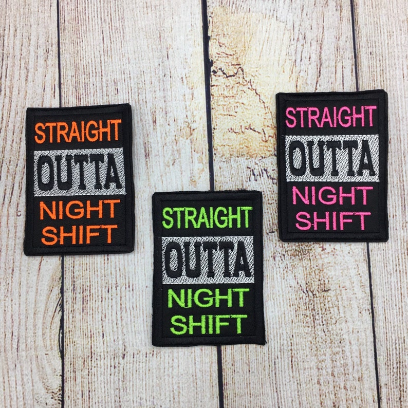 Op de afbeelding: Drie zwarte stoffen patches met witte stiksels. Elke patch zegt "Straight Outta Night Shift" in verschillende kleuren garen. De bovenste patch heeft oranje garen, de middelste patch heeft groen garen en de onderste patch heeft roze garen.