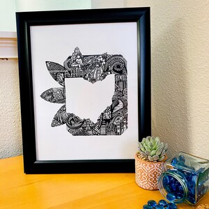 May include: Black framed art print featuring a detailed black and white illustration of the state of Ohio. The artwork is filled with intricate patterns and architectural details. The print is displayed on a wooden surface, with a small potted succulent and a jar of blue glass beads.