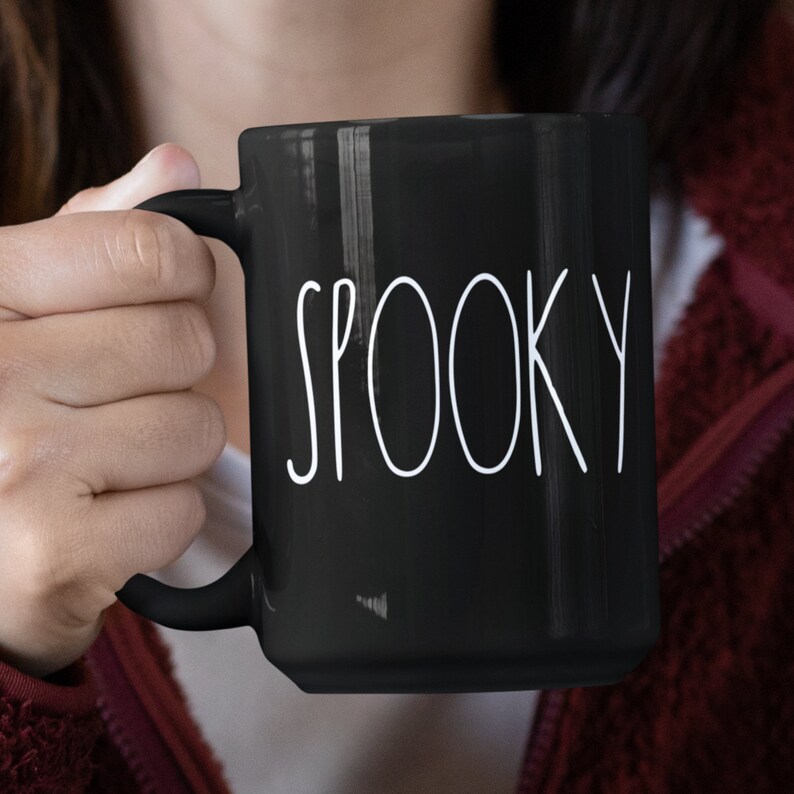 May include: A black ceramic mug with a white inscription that reads "SPOOKY".