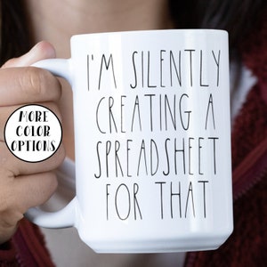 May include: White ceramic mug with black text that reads "I'm silently creating a spreadsheet for that".