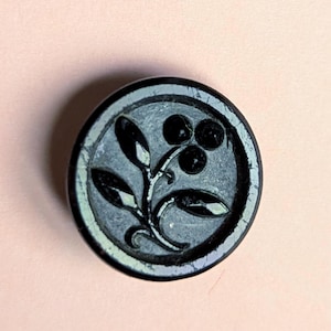 Antique small button black glass with with raised faceted style flower spring.1.2cm diameter.Signed.