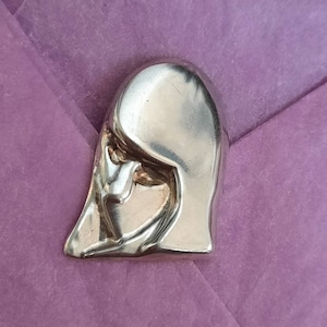 Button stylised female head in sterling silver. 30.4mm by 19.5mm diameter. Weight 4.1gram each.