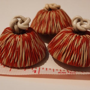 Può includere: Tre ornamenti a forma di cupola intrecciati a strisce rosse e bianche con cime in ceramica bianca.