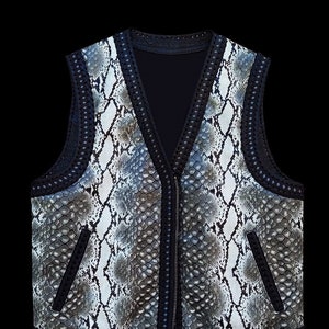 Pode incluir: Um colete de pele de cobra preto e branco com fecho de correr e guarnição de crochê preto.