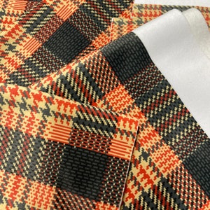 Peut inclure: Gros plan de plusieurs morceaux de tissu à motif écossais. Le motif écossais présente un mélange de couleurs noir, rouge et beige. Certaines pièces ont un dos blanc. Le tissu est probablement utilisé pour des projets de couture ou d'artisanat.