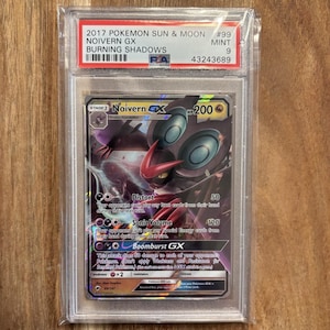 May include: A Pokemon trading card featuring Noivern GX from the Burning Shadows expansion. The card is in mint condition and has a PSA grading of 9. The card is a Stage 1 card with 200 HP and has three attacks: Distort, Sonic Volume, and Boomburst GX.