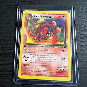 Könnte beinhalten: Eine Sammelkarte für das Pokémon Dunkles Glurak. Die Karte ist rot, schwarz und weiß. Sie zeigt ein rotes Glurak mit Flammen um sich herum. Die Karte hat ein Bild des Pokémon, seinen Namen und seine Werte. Die Karte stammt aus dem Game Boy Advance Spiel, Pokémon Sammelkartenspiel.