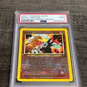 May include: A graded Pokémon card featuring Entei from the 2001 Pokémon 3 Movie Promo set. The card is encased in a protective holder and has a mint condition grade of 9. The card's artwork depicts a fiery, dog-like creature.
