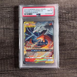 Puede incluir: Una carta Pokémon graduada con Reshiram & Charizard GX del set 2019 Sun & Moon Unbroken Bonds. La carta está dentro de un soporte protector, mostrando los detalles de la carta y una calificación de NM-MT 8.