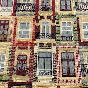 Puede incluir: Un tapiz con un patrón repetitivo de edificios coloridos con ventanas y balcones. Los edificios están representados en un estilo tejido con una superficie texturizada.