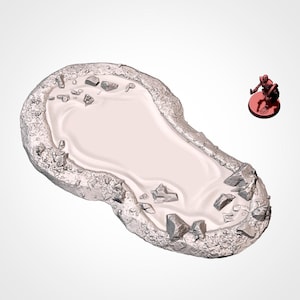 Op de afbeelding: Een wit, ovaalvormig, miniatuurvijver met een rotsachtige rand. De vijver is gevuld met water en heeft een paar kleine stenen die op de bodem zijn verspreid.