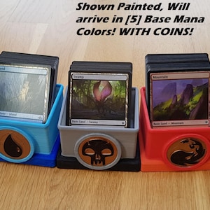 May include: Five square plastic card storage boxes in yellow, blue, gray, red, and green, each holding a deck of trading cards. Each box features a circular emblem on the front. Text reads: Shown Painted, Will arrive in [5] Base Mana Colors! WITH COINS!