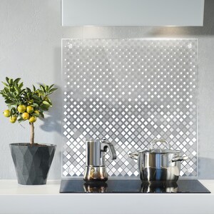 Könnte beinhalten: Eine moderne Küche mit einer Glasrückwand mit geometrischem Muster. Ein silberner Topf und eine silberne Kaffeemaschine stehen auf dem Herd.
