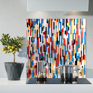 May include: A modern kitchen backsplash with a colorful geometric pattern in shades of blue, red, yellow, and black. A silver pot and a silver coffee maker are on a black stovetop in front of the backsplash.