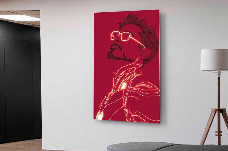 Puede incluir: Una impresi&oacute;n en lienzo roja que presenta una ilustraci&oacute;n estilizada de un hombre mirando hacia arriba. La obra de arte utiliza una combinaci&oacute;n de colores rojo y blanco, con l&iacute;neas blancas brillantes que delinean la figura y las gafas. El arte est&aacute; montado en una pared blanca.