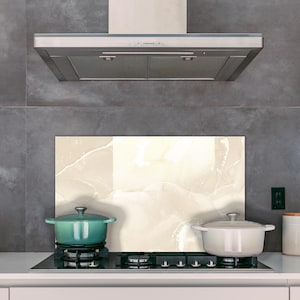 May include: A white marble backsplash with a light brown veining pattern is installed above a black electric stovetop with two pots on it. One pot is teal and the other is white.