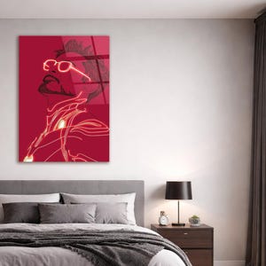 Puede incluir: Una impresi&oacute;n art&iacute;stica de pared roja con una ilustraci&oacute;n estilizada de una persona con gafas, barba y un dise&ntilde;o futurista. La obra de arte est&aacute; delineada en un color ne&oacute;n brillante.