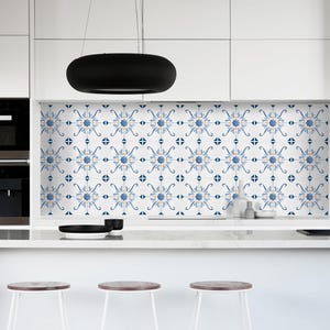Könnte beinhalten: Moderne Küche mit weißen Schränken, einer Marmorarbeitsplatte und einem gemusterten Fliesenspiegel mit blau-weißen Blumendesigns. Ein schwarzer Wasserhahn und eine schwarze ovale Leuchte sind ebenfalls zu sehen.