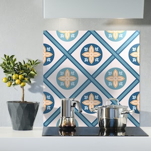 Puede incluir: Un protector de salpicaduras de cocina con un patrón de azulejos azul y blanco que presenta un diseño geométrico repetitivo con acentos naranjas. Un árbol de cítricos en maceta y una cafetera están en la encimera frente al protector de salpicaduras.