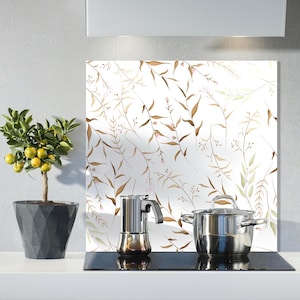 May include: A kitchen setting with a small potted lemon tree, a stainless steel stovetop espresso maker, and a stainless steel pot. A decorative panel with a botanical design is in the background.
