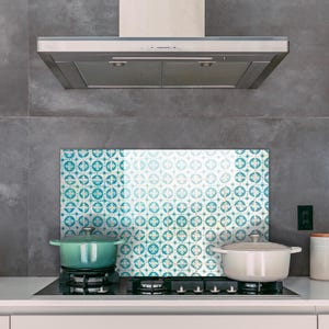 May include: A kitchen with a stainless steel range hood, a white tiled backsplash with a blue and white pattern, and two pots on the stovetop.