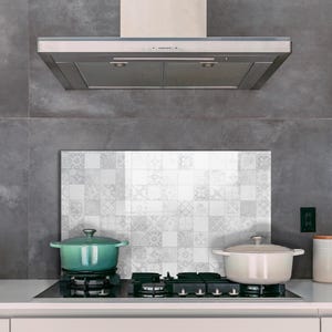 Könnte beinhalten: Eine moderne Küche mit einer Edelstahl-Dunstabzugshaube über einem Kochfeld mit zwei Töpfen. Ein türkisfarbener Topf steht links, ein cremefarbener Topf rechts. Eine weiße Rückwand mit Muster befindet sich hinter dem Kochfeld.