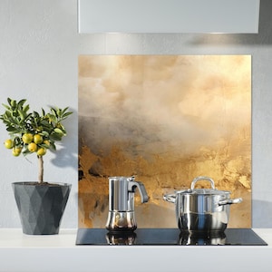 May include: A kitchen scene featuring a small potted lemon tree with yellow fruit, a stainless steel stovetop espresso maker, and a stainless steel pot with a glass lid. A decorative panel with gold and brown tones is in the background.