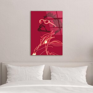 Puede incluir: Una impresi&oacute;n art&iacute;stica mural roja que presenta una ilustraci&oacute;n estilizada de una persona con gafas. La obra de arte utiliza una combinaci&oacute;n de colores rojo y blanco, con el contorno y los detalles de la figura resaltados en blanco sobre un fondo rojo. El arte se exhibe sobre una cama.