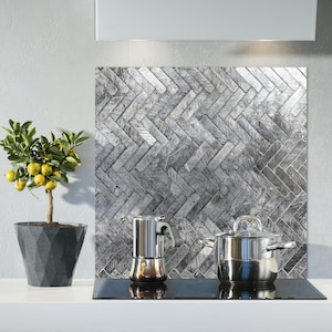 Peut inclure: Une scène de cuisine avec un petit citronnier en pot portant des fruits jaunes, une table de cuisson en acier inoxydable et une crédence avec un motif en chevrons gris. Une cafetière et une casserole en acier inoxydable sont sur la table de cuisson.