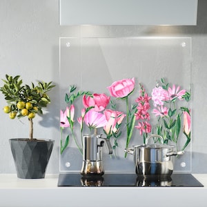 May include: A clear glass kitchen splashback with a floral design featuring pink and white flowers. The splashback is installed above a hob with a coffee pot and a silver pot.