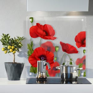 Puede incluir: Una escena de cocina con un protector contra salpicaduras de vidrio adornado con amapolas rojas. Una olla de acero inoxidable y una cafetera italiana están sobre una placa de cocina negra. Un limonero en maceta añade un toque de vegetación.