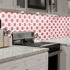 May include: A white kitchen with red and white patterned tile backsplash, a stainless steel hob, and white cabinets.