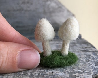 Escultura de hongo en miniatura de lana blanca afieltrada con aguja de pequeños hongos.