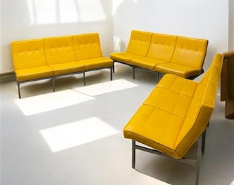 May include: A set of five yellow mid-century modern sofas with black metal frames. The sofas are arranged in a semi-circle, with two three-seater sofas and three single-seater sofas.