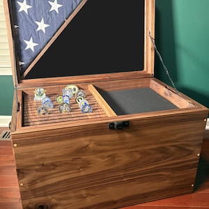 May include: A wooden display case with an open lid, showcasing a section of the American flag and a black background. The interior features a compartment with various coins. The case is made of dark wood and has a hinged lid.