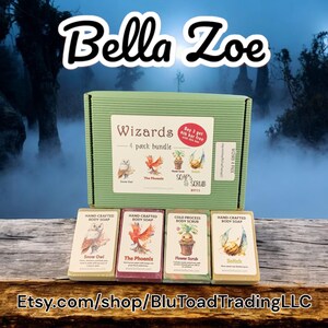 May include: A green box set of four bars of soap with the text "Wizards 4 pack bundle". The soap bars are labeled "Snow Owl", "The Phoenix", "Flower Scrub", and "Selich". The brand name "Bella Zoe" is at the top.