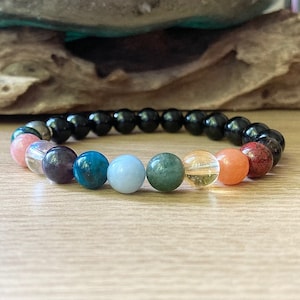 May include: A bracelet with black beads and colourful gemstone beads. The gemstone beads are pink, purple, green, blue, yellow, and orange.